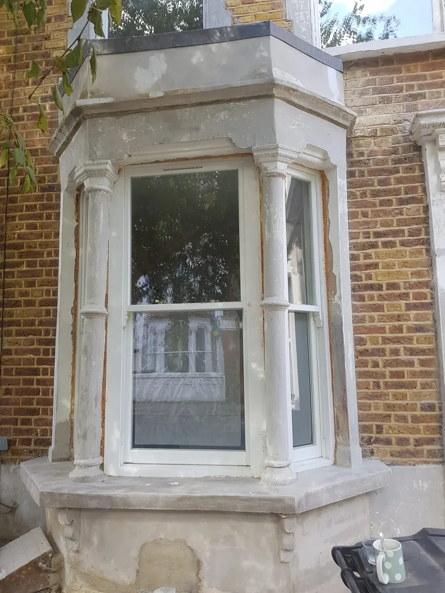 A bay window with weathered stonework and peeling paint