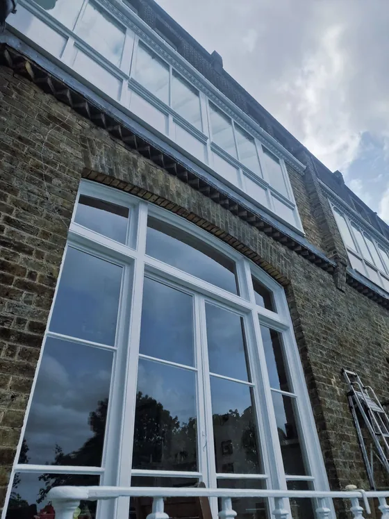 Tall arched window with white painted frames in a brick building