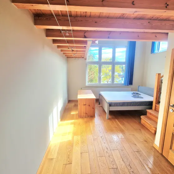 Bedroom with exposed timber beams, white walls and an oak floor