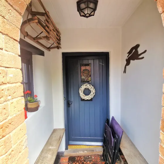 Dark grey front door with a wreath, in a white porch