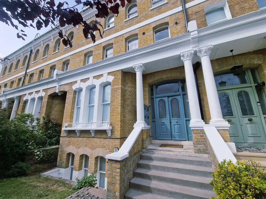 A Victorian brick terrace with white stone columns and a teal front door