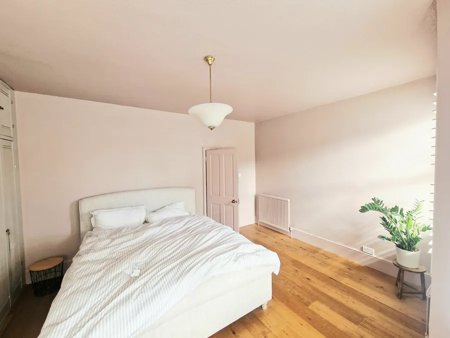 A bedroom with white walls, an oak floor and a double bed