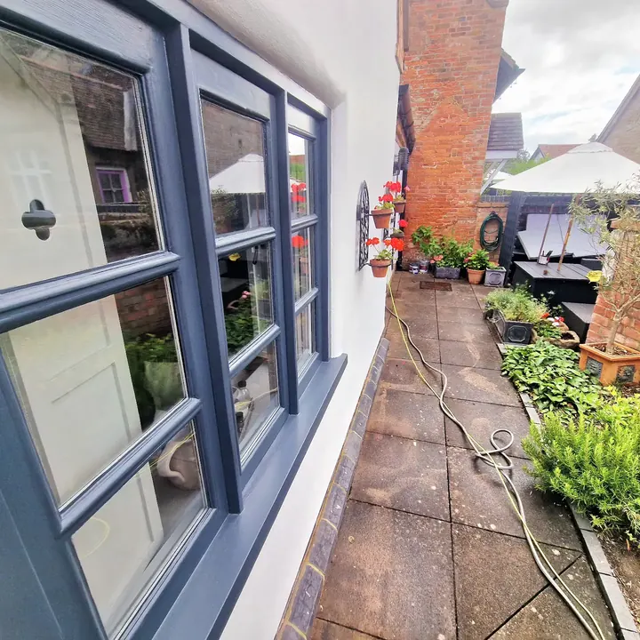 A finished window painted dark grey in a white rendered wall